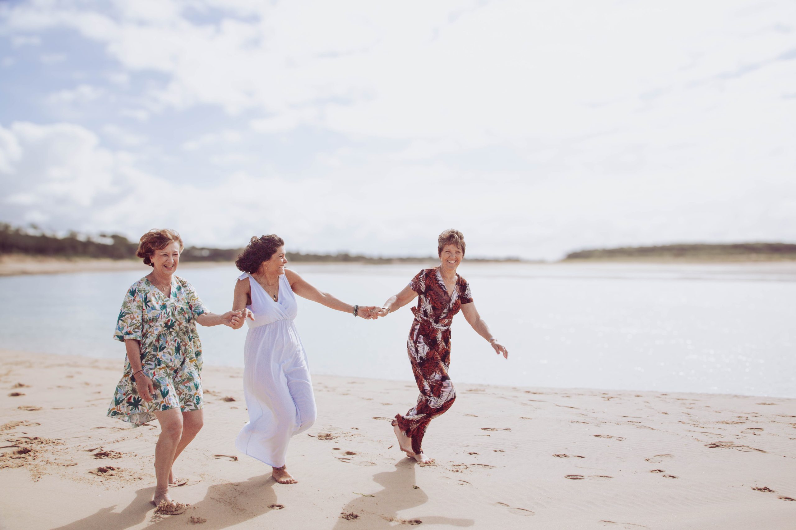 Tri dressing Trois femmes courant sur une plage mains dans la main.