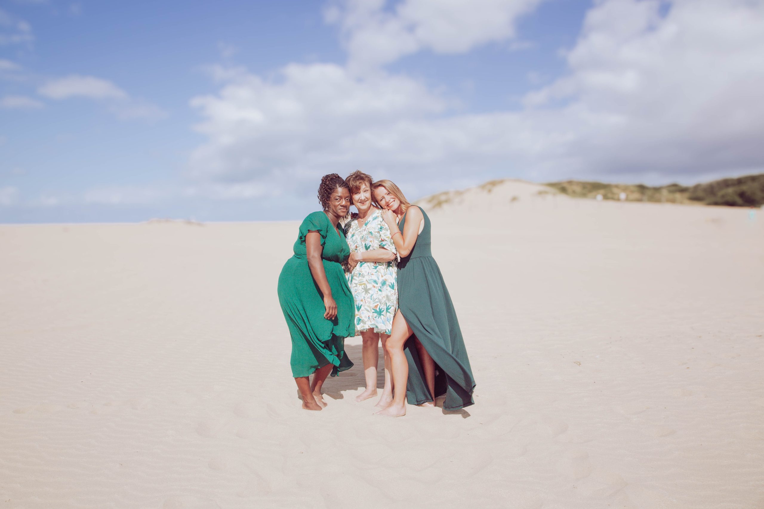 Accompagnement shopping Trois femmes sur une plage collées les uns aux autres de manière amicale en souriant.